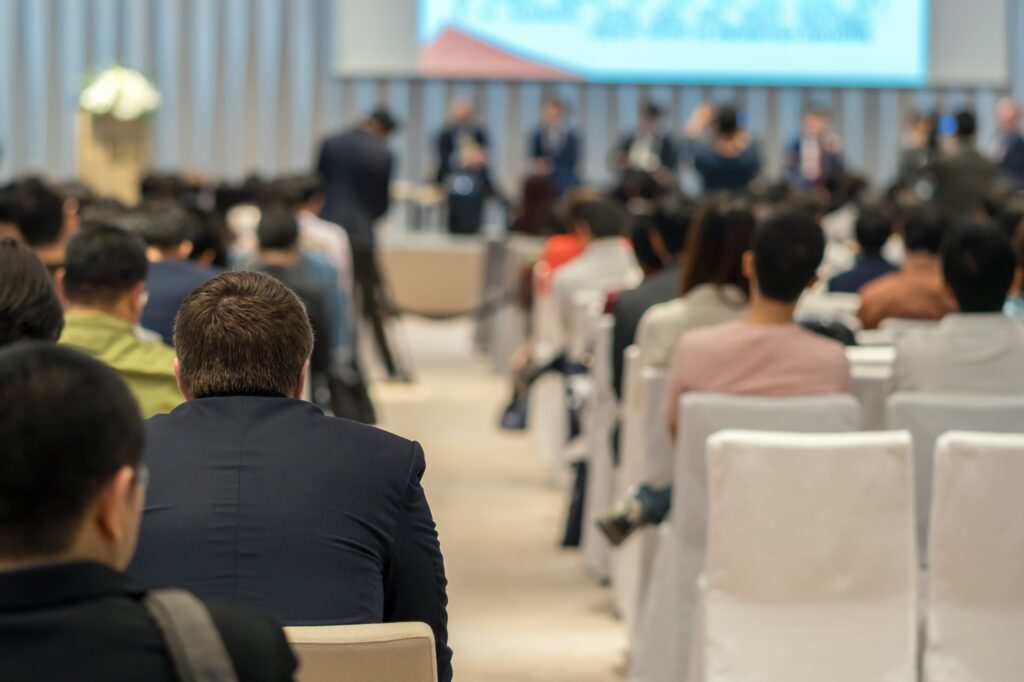 Multilingual speakers on the stage with Rear view of Audience in the conference hall or seminar meeting